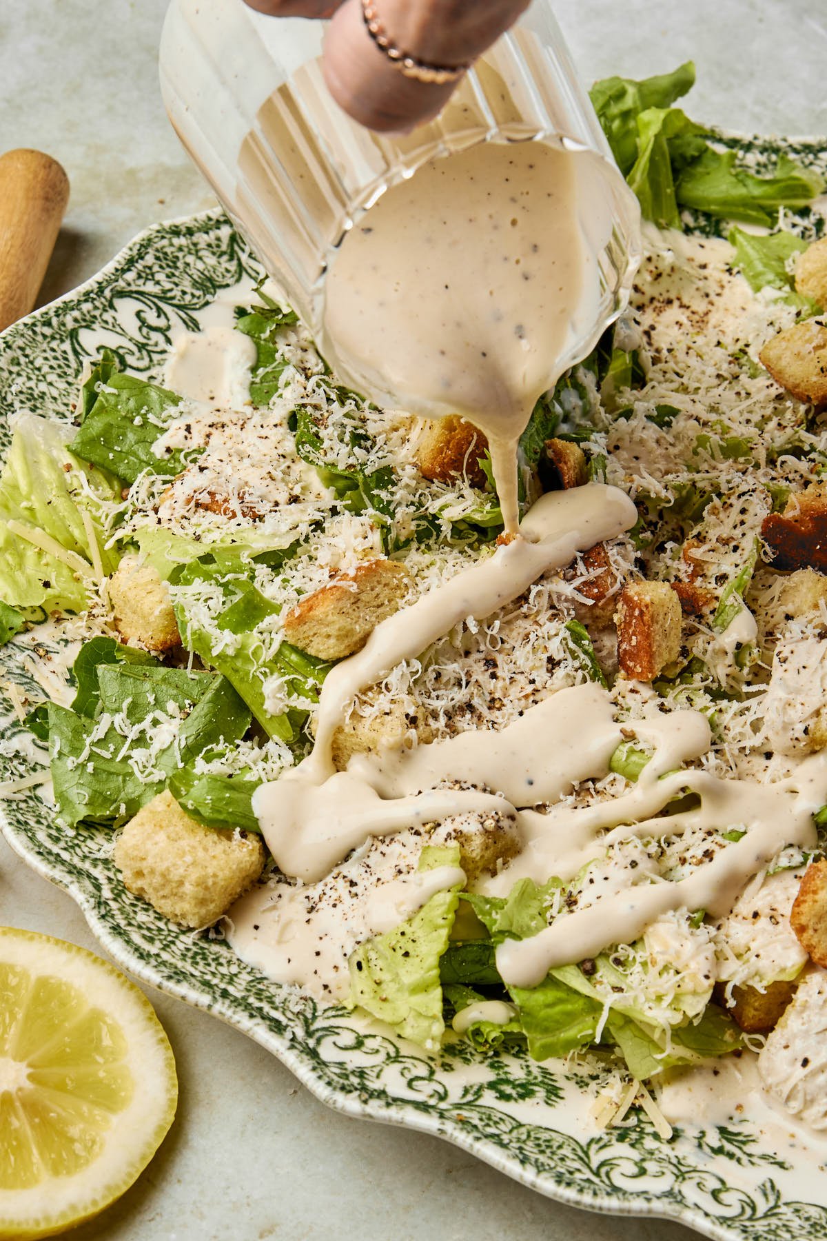 a container of this caesar dressing recipe poured over a salad