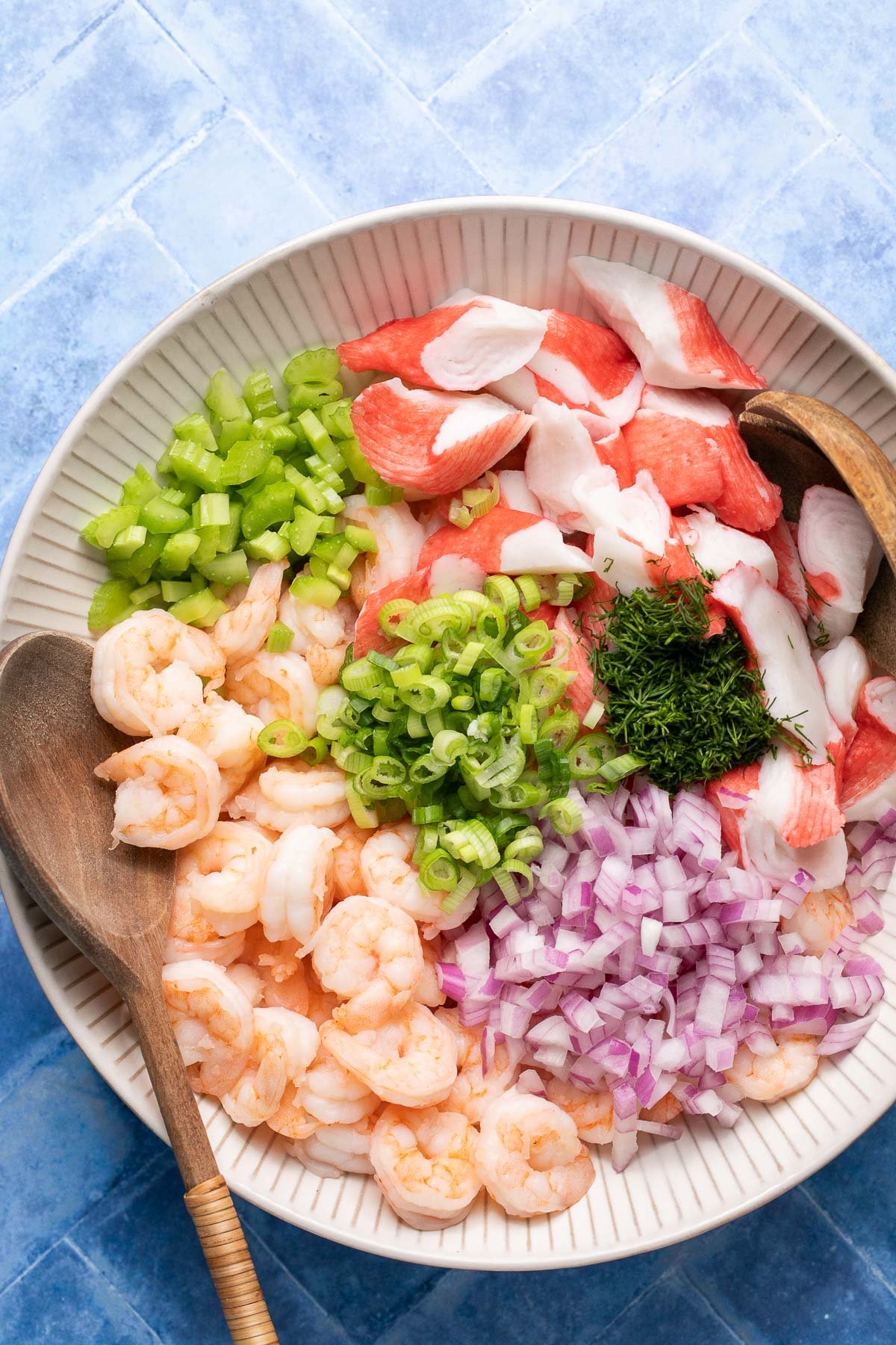 a seafood salad in a large white bowl before it is tossed