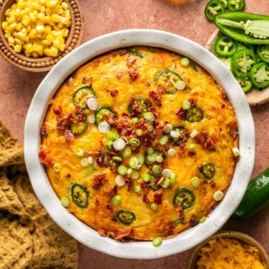 an overhead shot of cornbread casserole topped with bacon and green onion