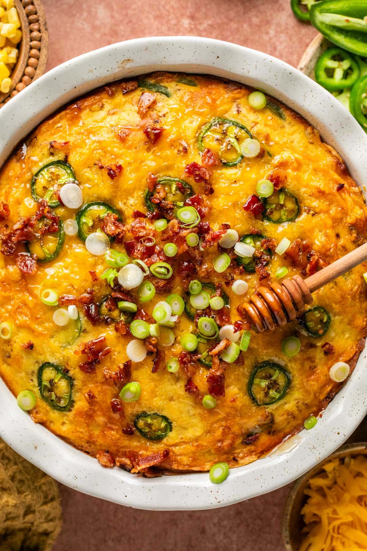 an overhead shot of cornbread casserole topped with bacon and green onion