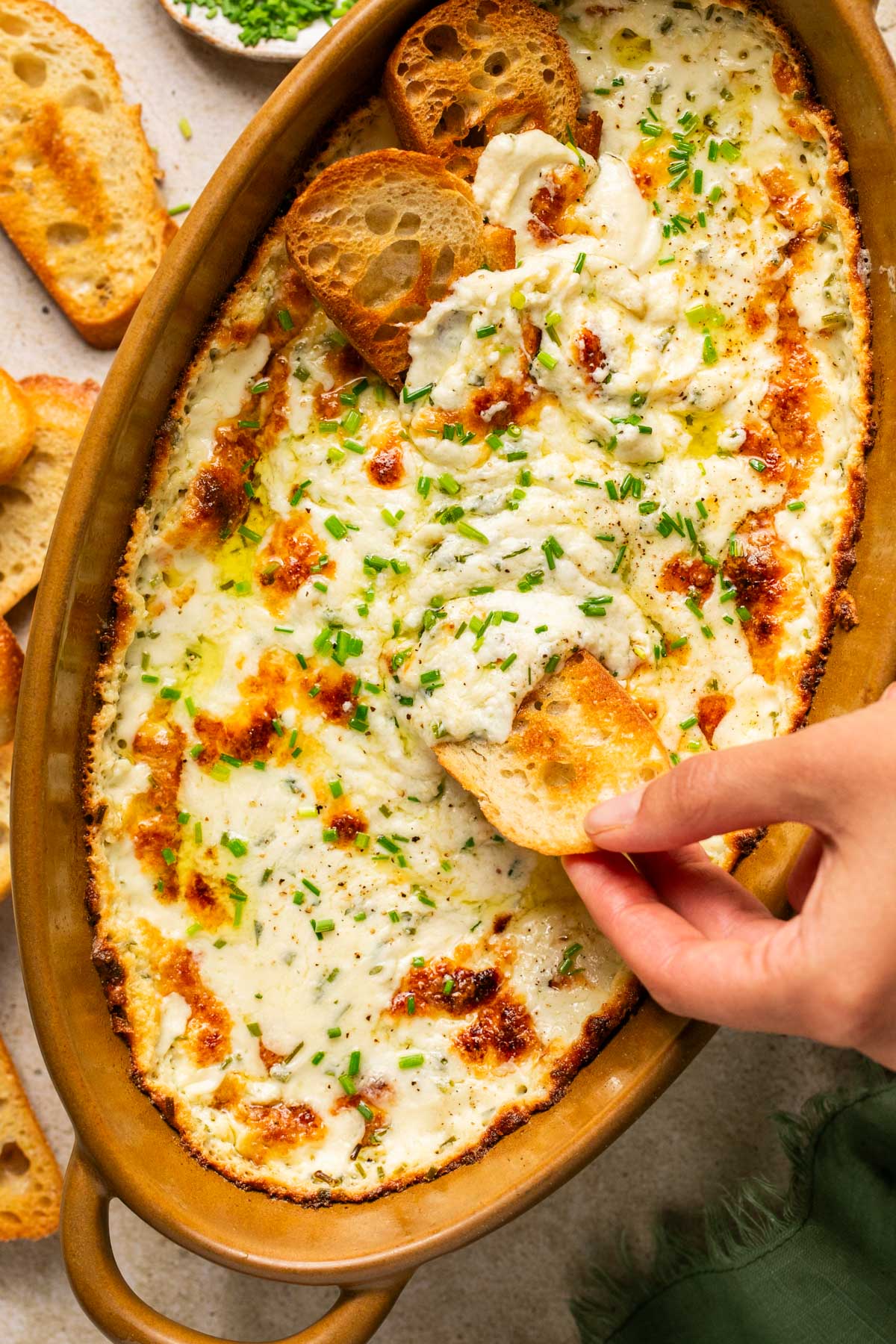 a hand dipping a slice of bread into dip