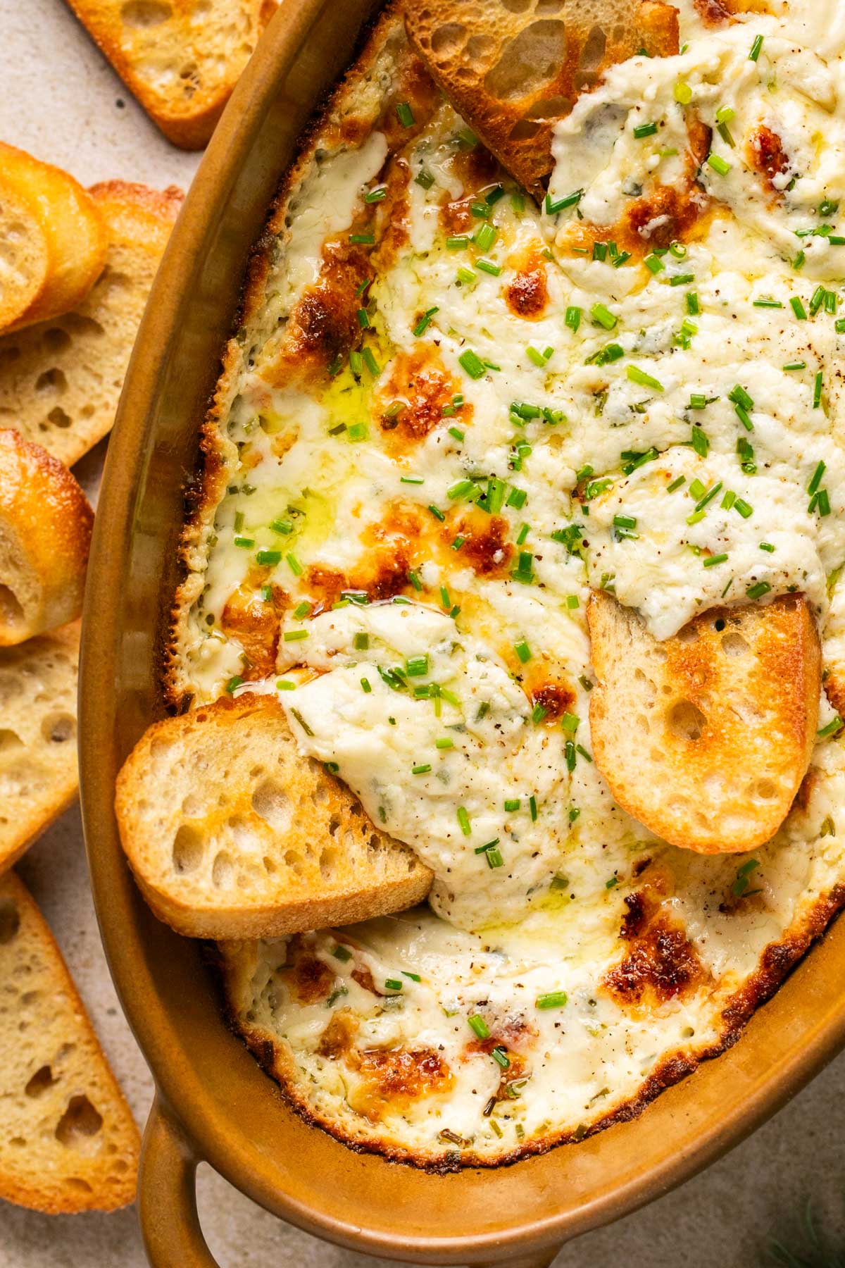 and up close shot of garlic bread dip with crostini dipping into it