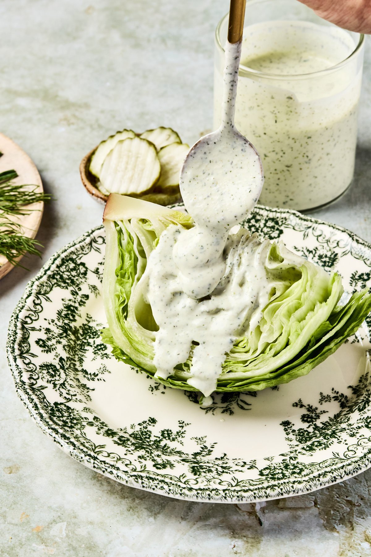 a spoon drizzling cottage cheese ranch over a wedge of lettuce