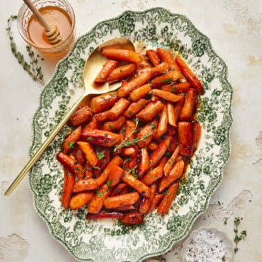 a platter filled with maple glazed carrots with a gold serving spoon