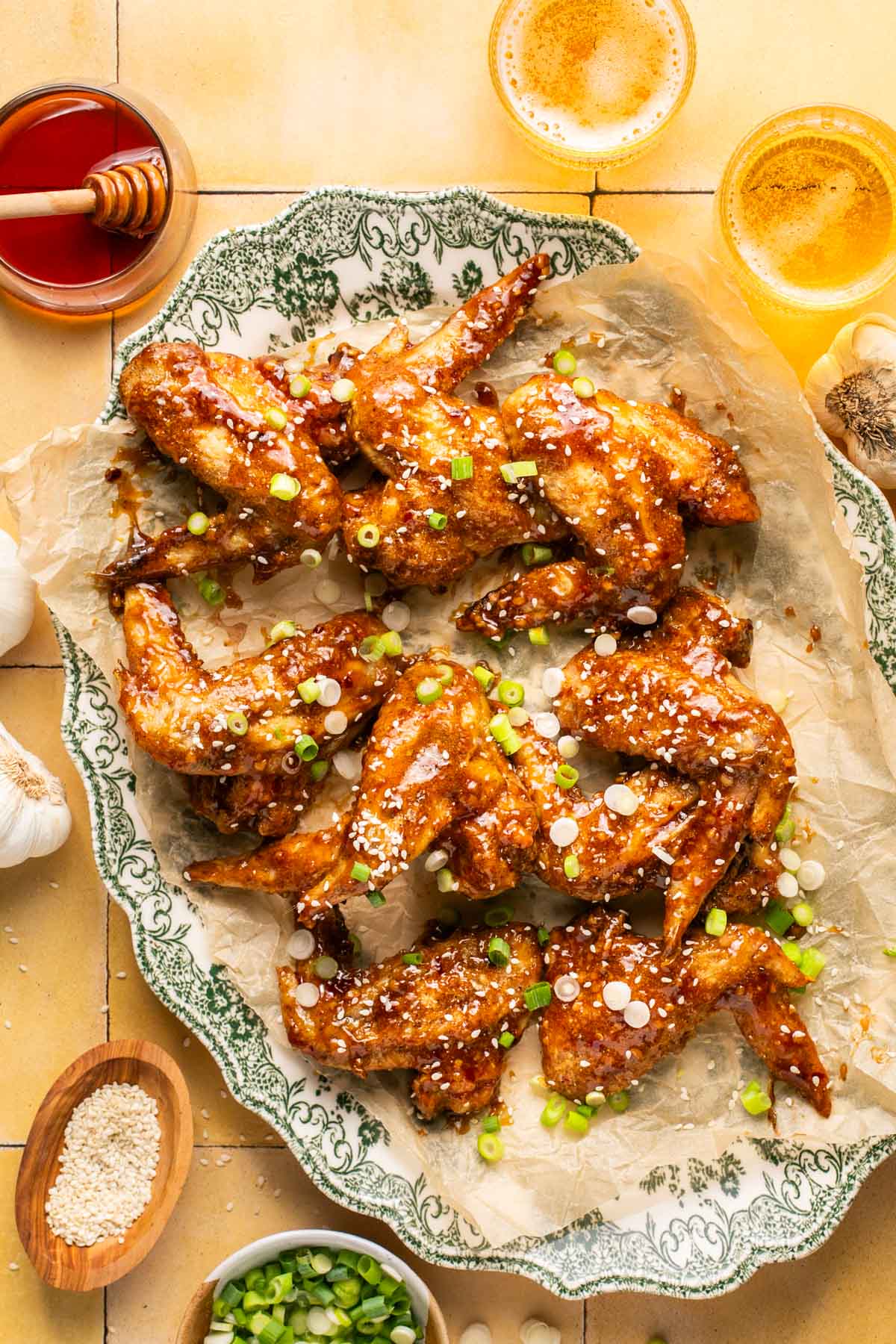 honey baked wings on a serving platter topped with sesame seeds and chopped green onions