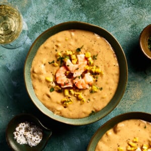 an overhead shot of shrimp and corn chowder in a bowl with a green background