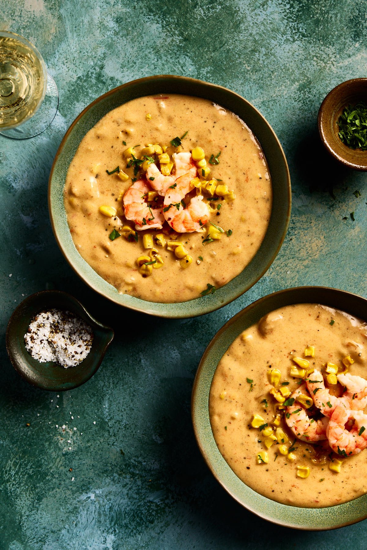 an overhead shot of shrimp and corn chowder in a bowl with a green background 