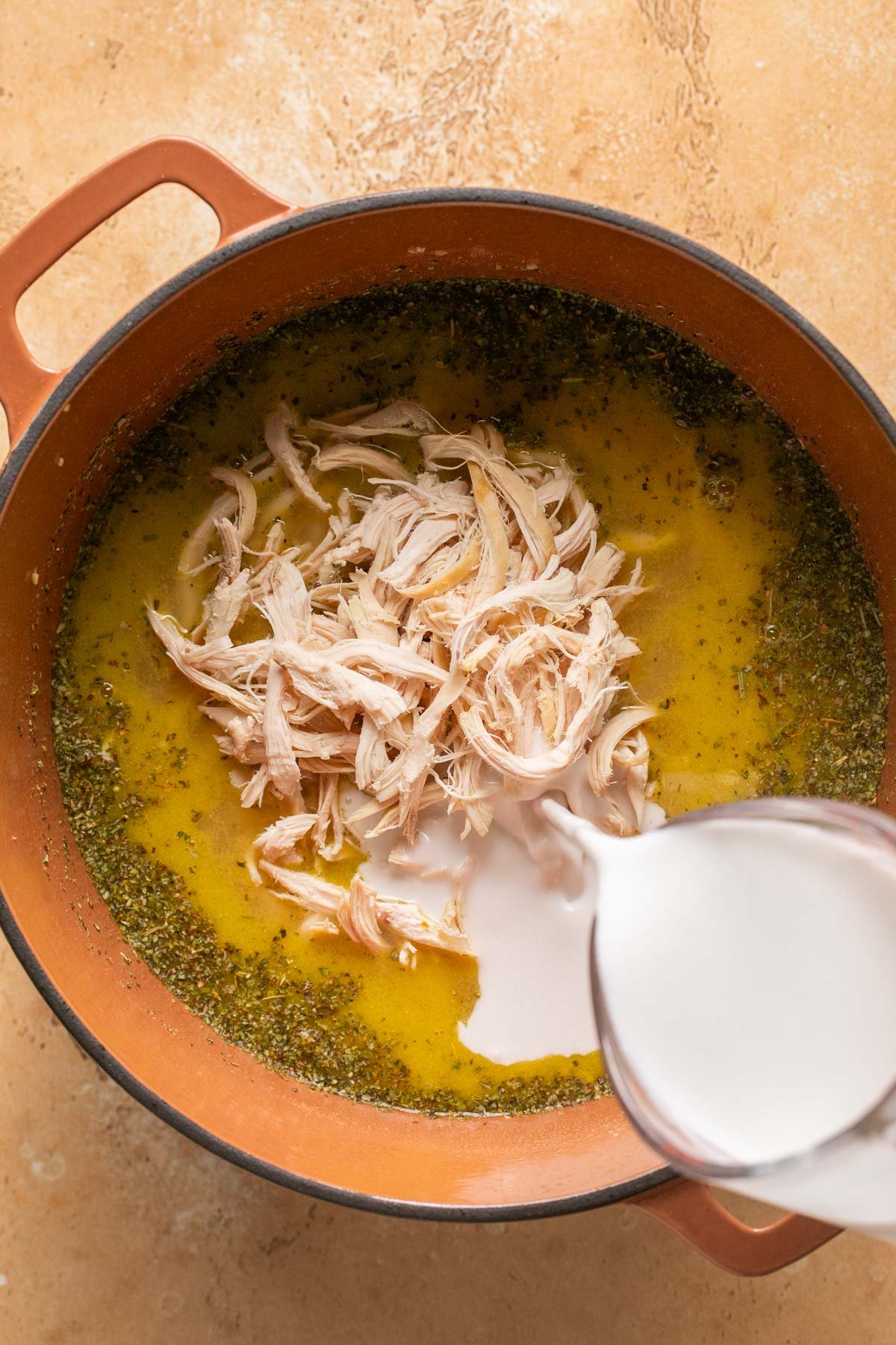 adding cream and chicken to the soup pot 