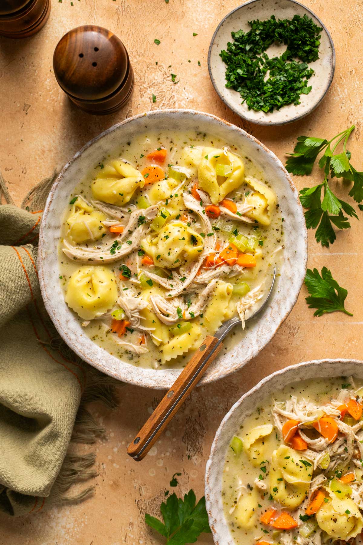 a bowl of creamy chicken tortellini soup with a spoon resting on the side 