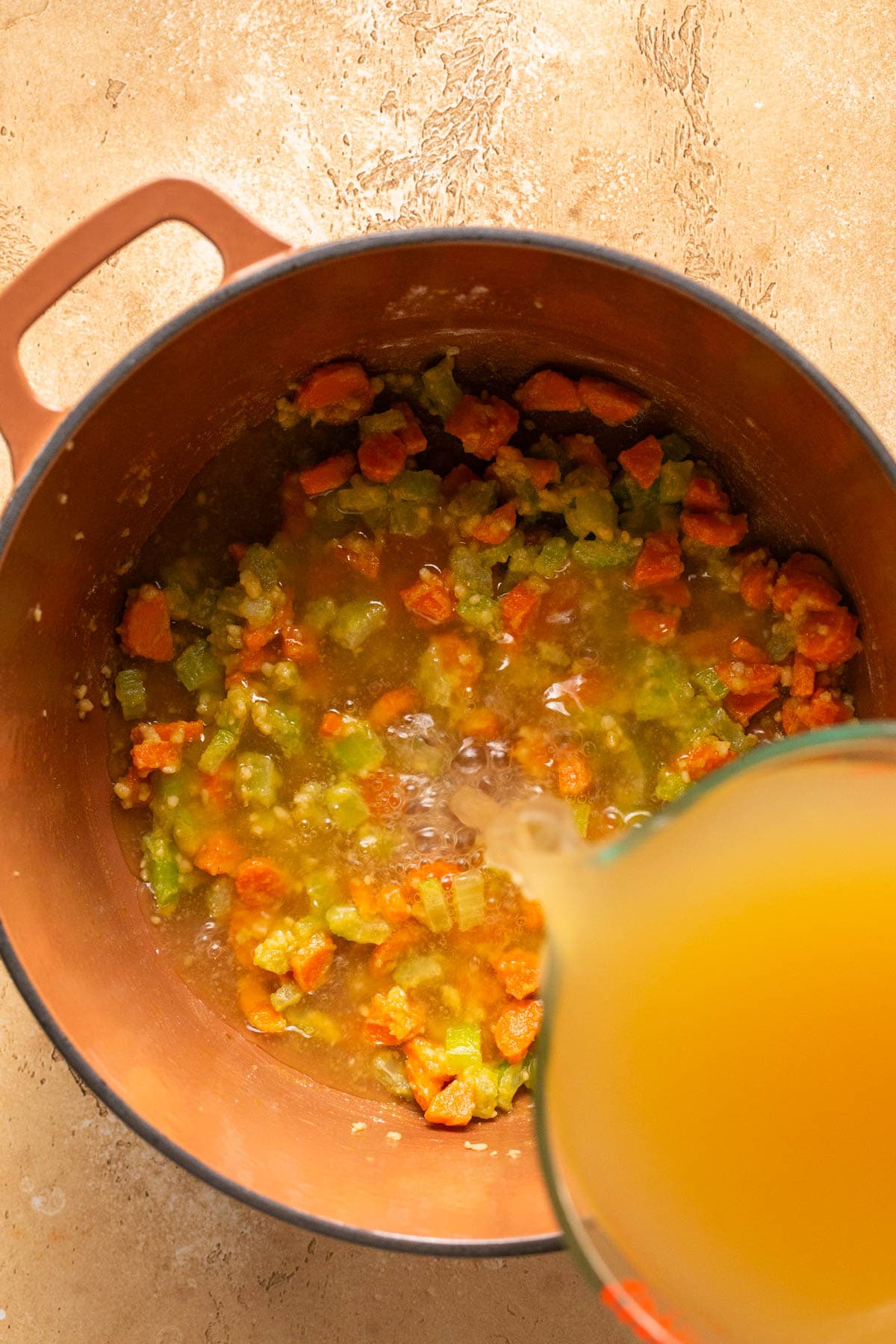 pouring broth into a soup pot 