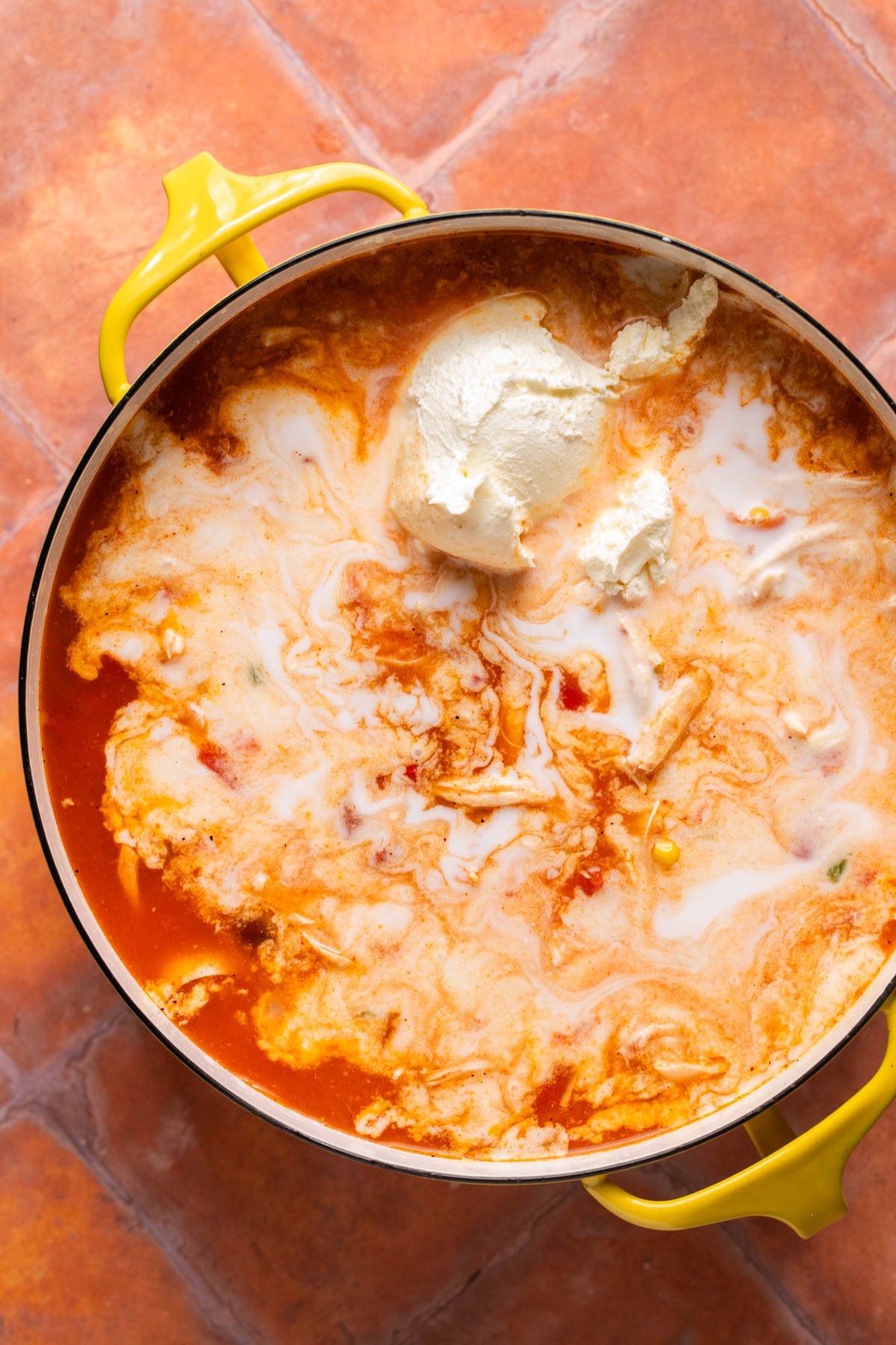 adding sour cream to make the chicken tortilla soup extra creamy 