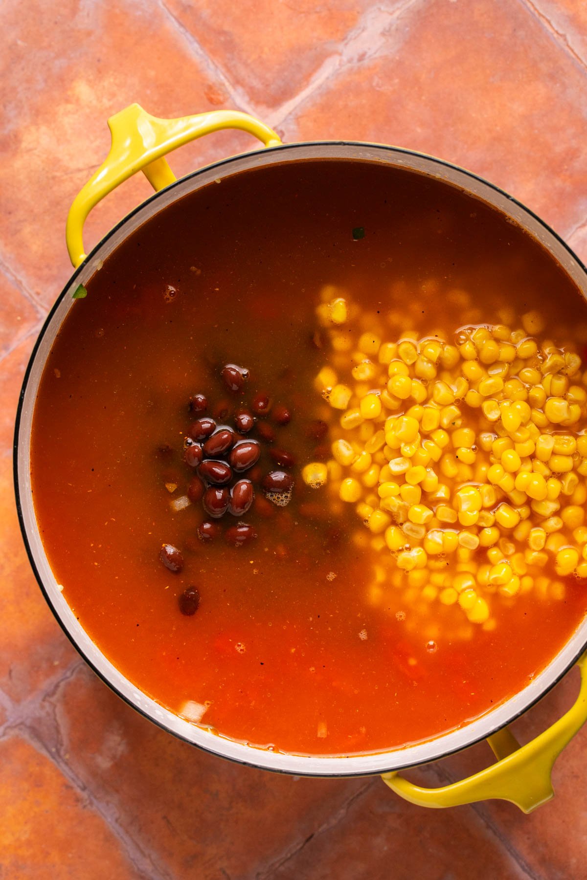 adding black bean and corn to the soup pot