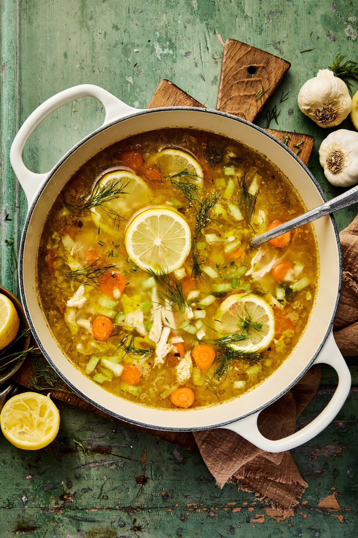 a large pot of lemon chicken soup with a ladle resting inside