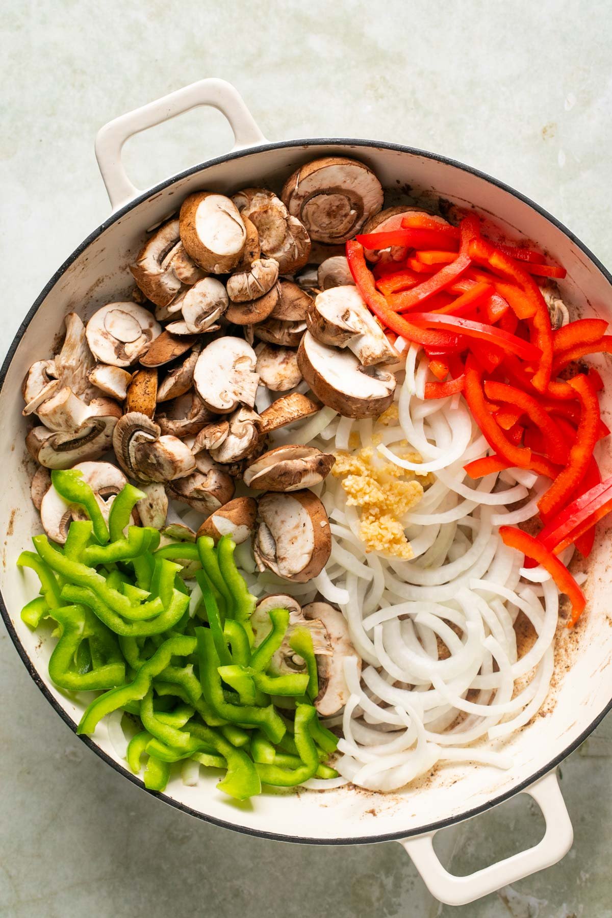 sliced raw veggies in a skillet 