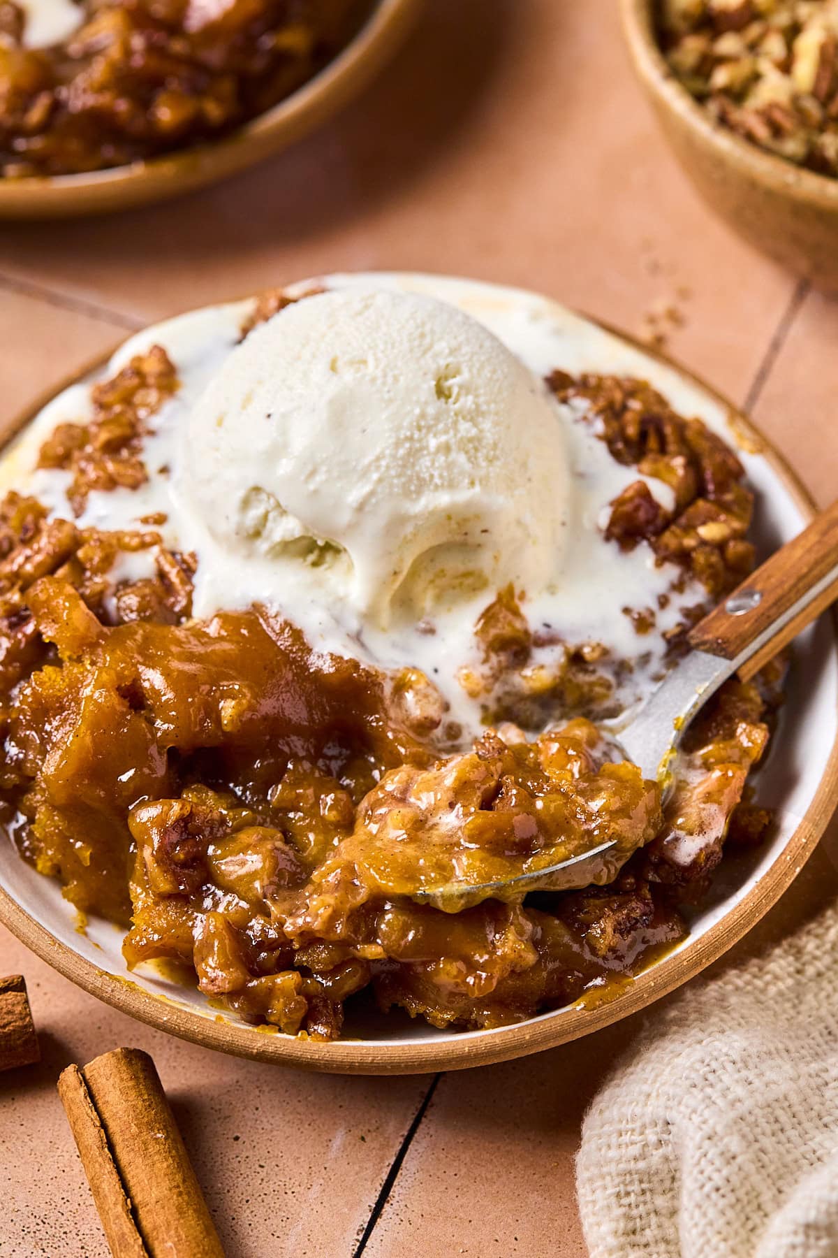 a slice of pumpkin cobbler in a bowl topped with vanilla ice cream.