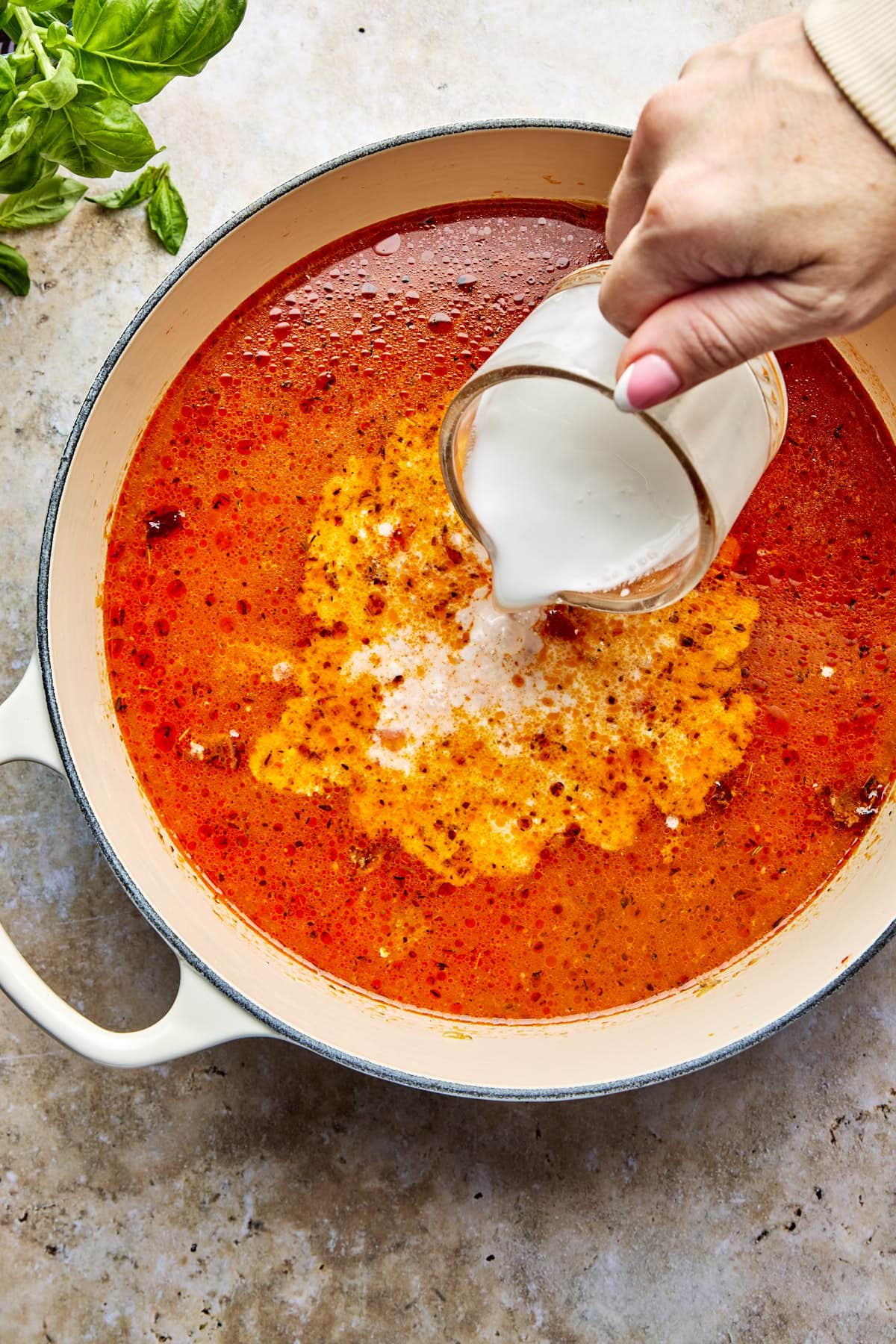 adding coconut milk to a soup pot