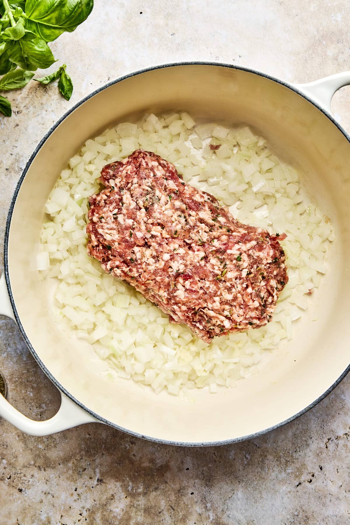 italian sausage cooking on top of onions in a soup pot