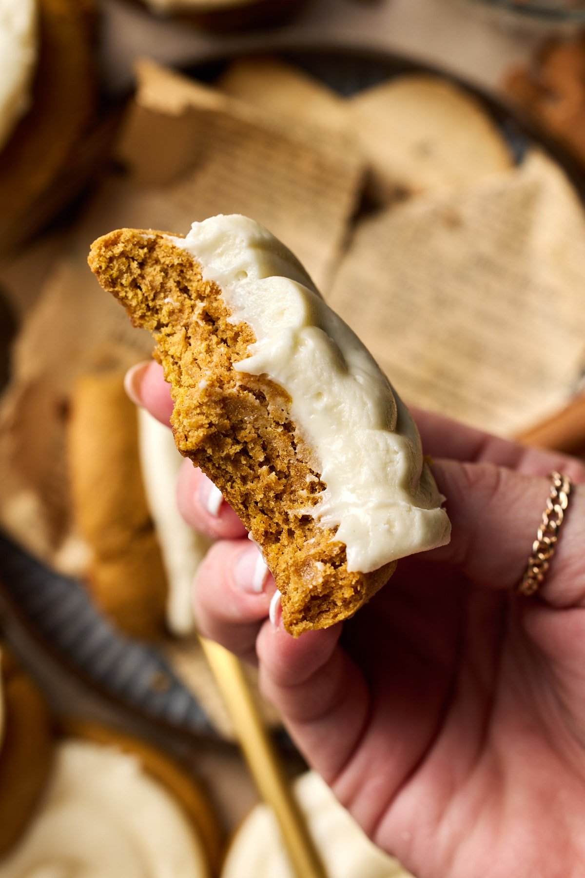 a hand holding half of a pumpkin cookie to show the middle 