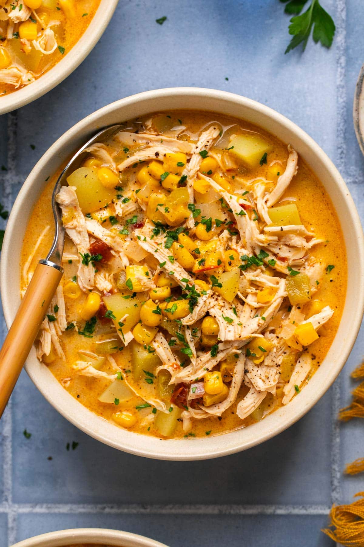 an overhead shot of chowder topped with herbs, corn, and chicken