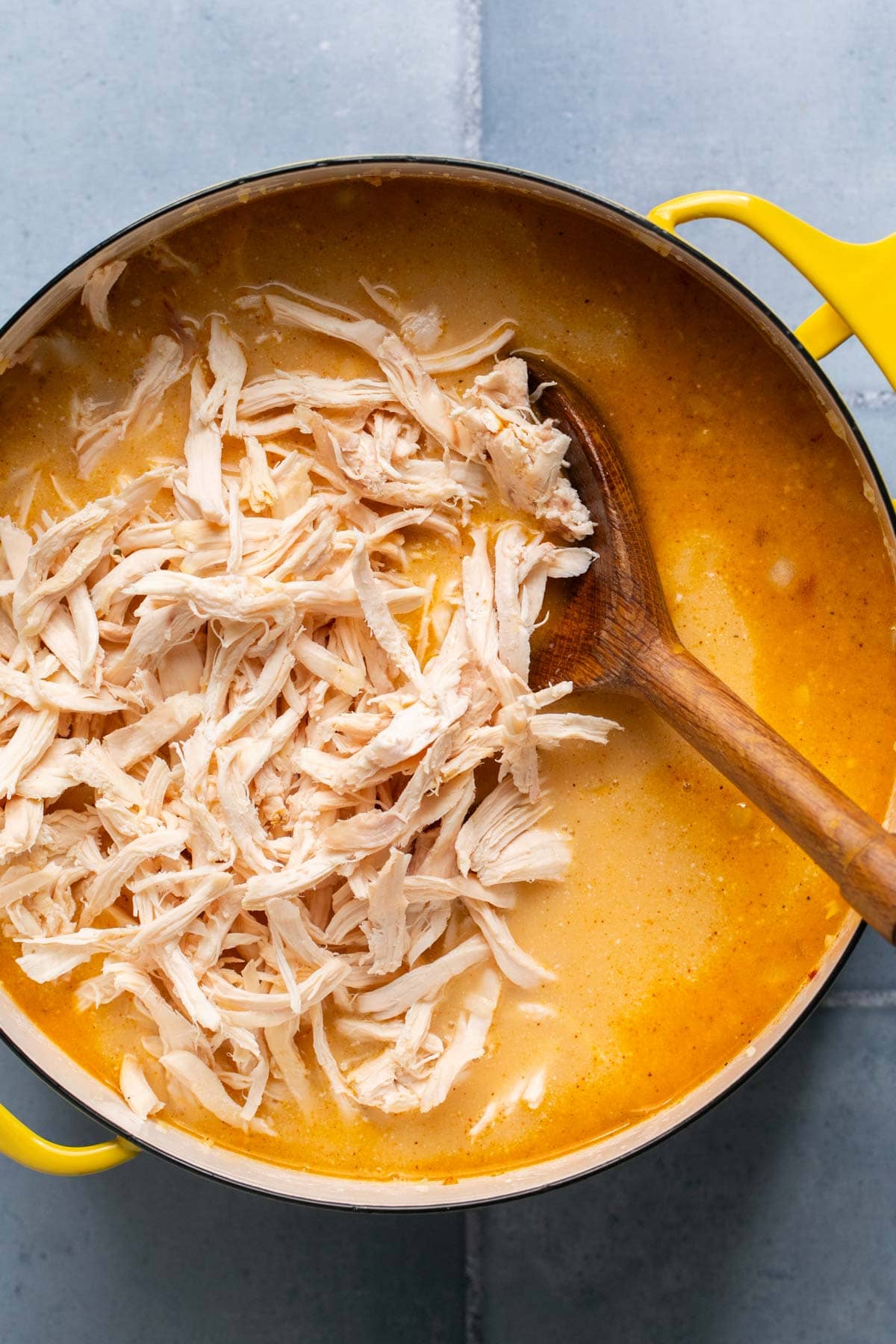 adding shredded chicken to a soup pot