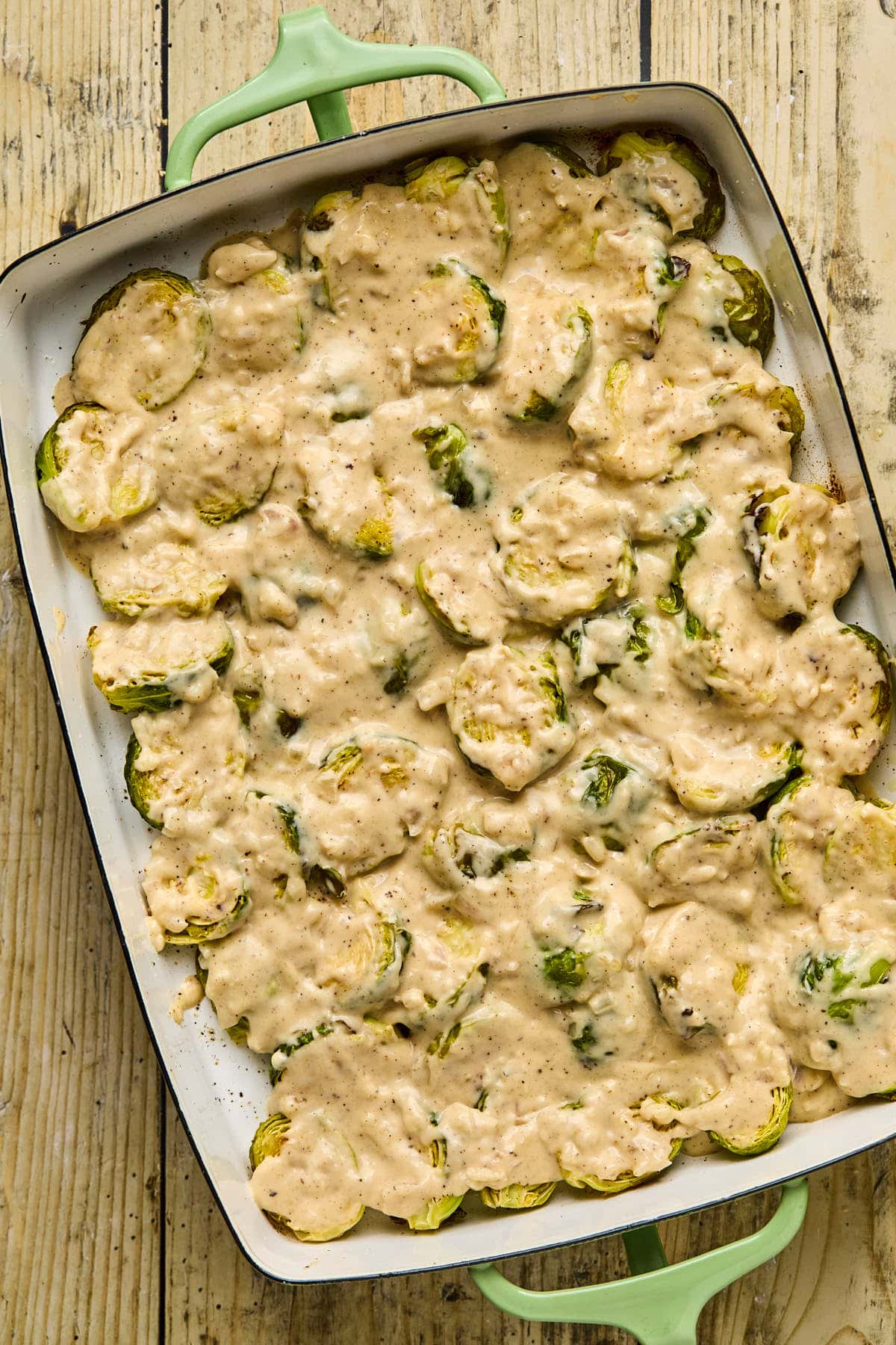 a baking dish filled with brussels sprouts and a creamy sauce poured over top