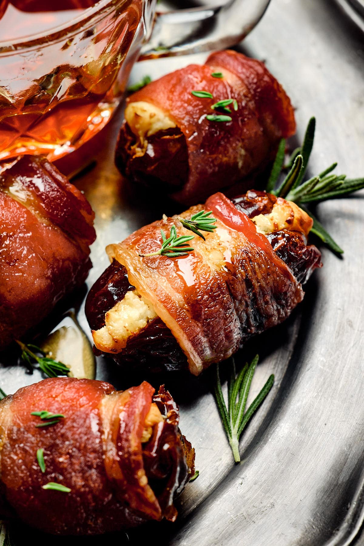 stuffed dates wrapped in bacon and topped with rosemary