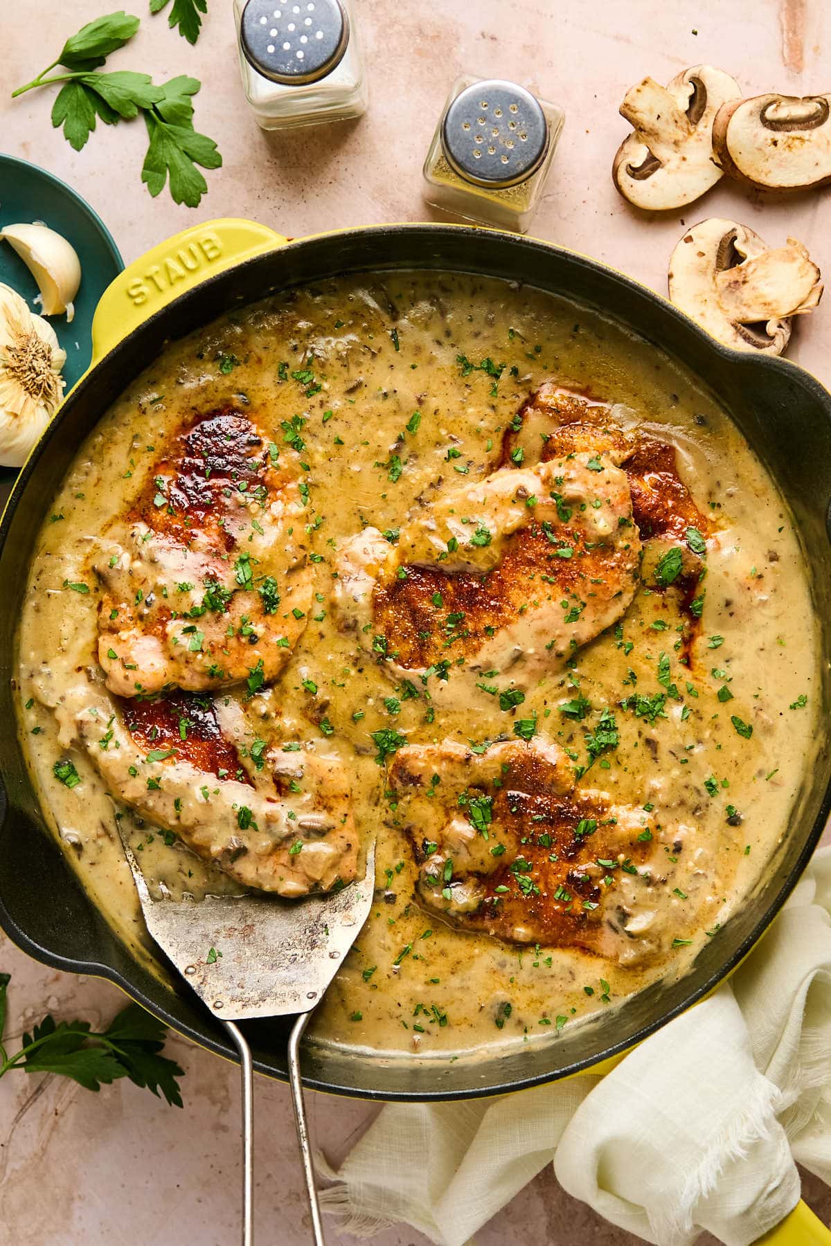 cream of mushroom pork chops in a skillet with sauce and fresh herbs. 