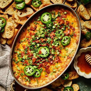 baked hot honey jalapeno popper dip topped with green onions, jalapeno, and bacon.