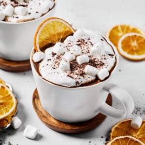 dairy-free hot chocolate in a mug topped with whipped cream, marshmallows, and chocolate shavings.