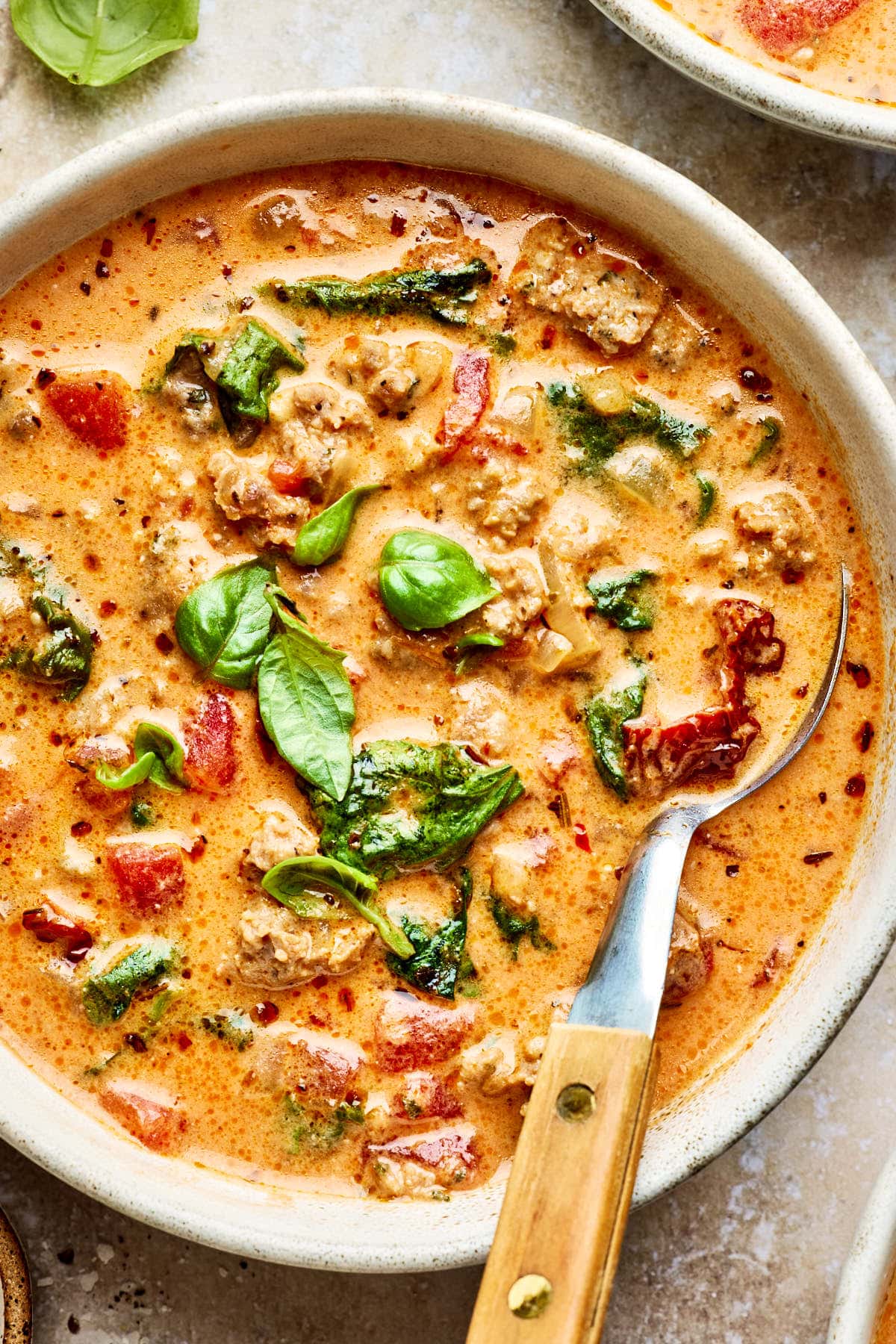 a bowl of italian sausage soup topped with fresh basil.