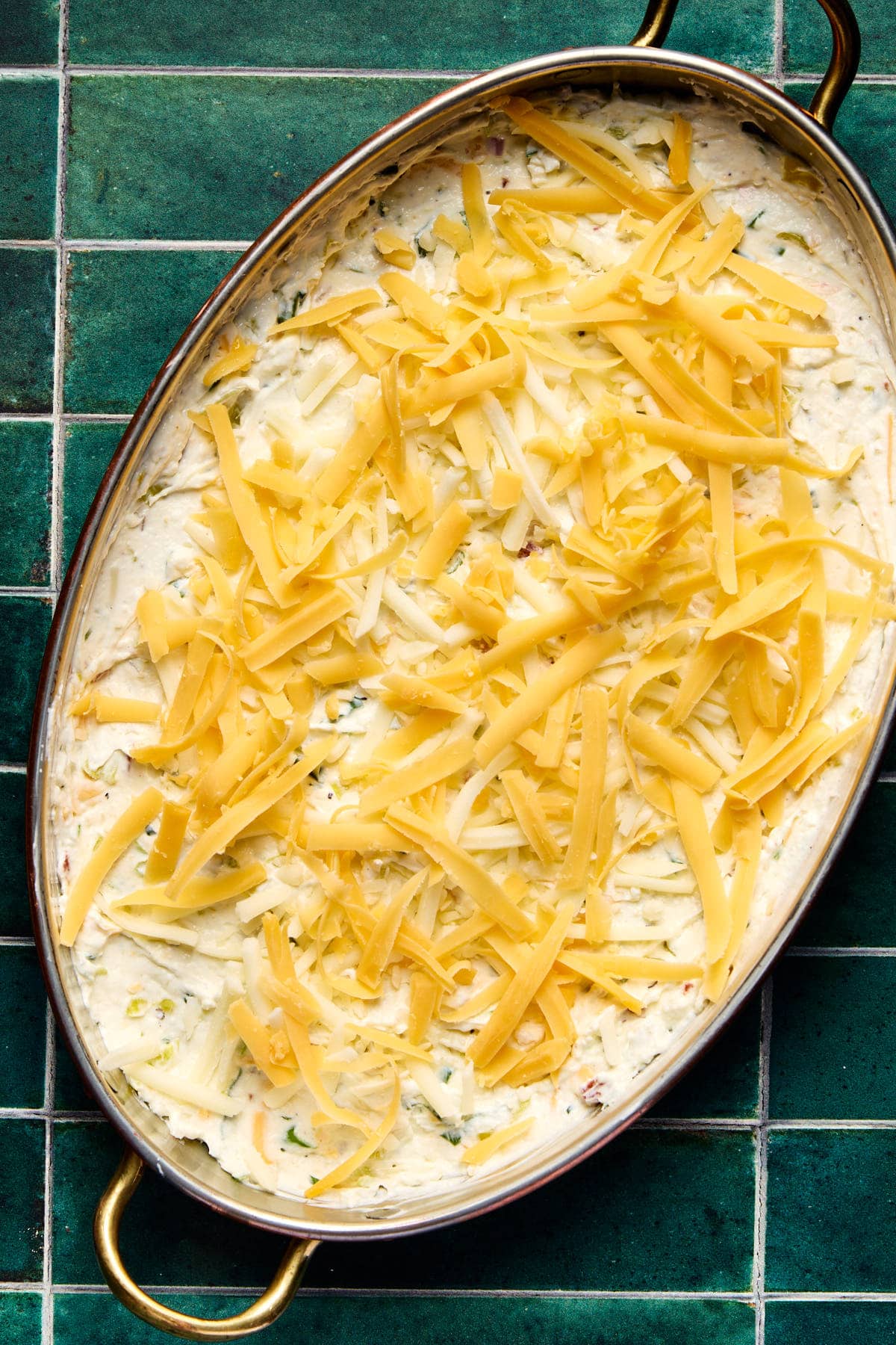 shredded cheese on top of the dip in a baking dish 