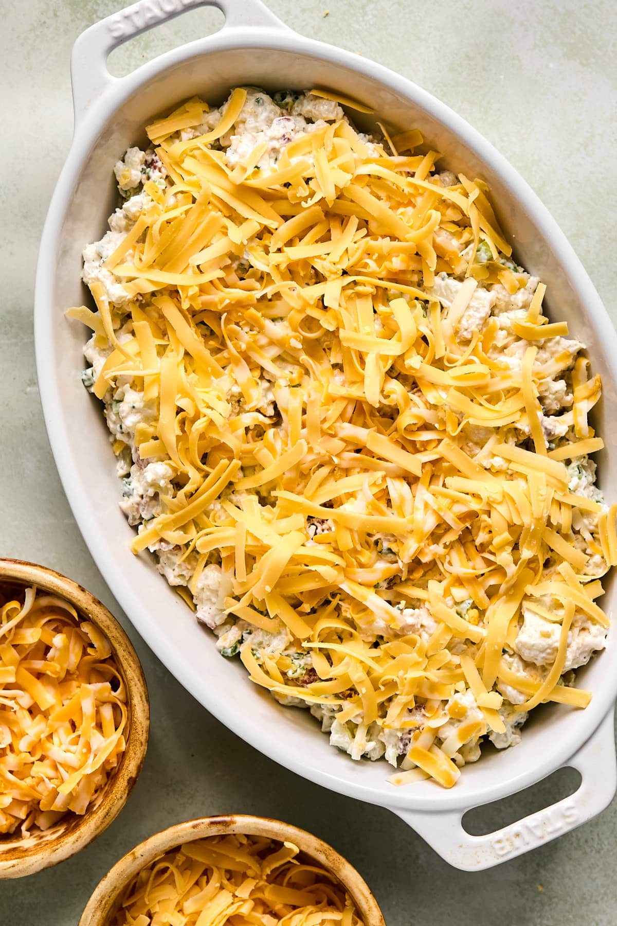 the cauliflower filling in a baking dish topped with grated cheddar cheese