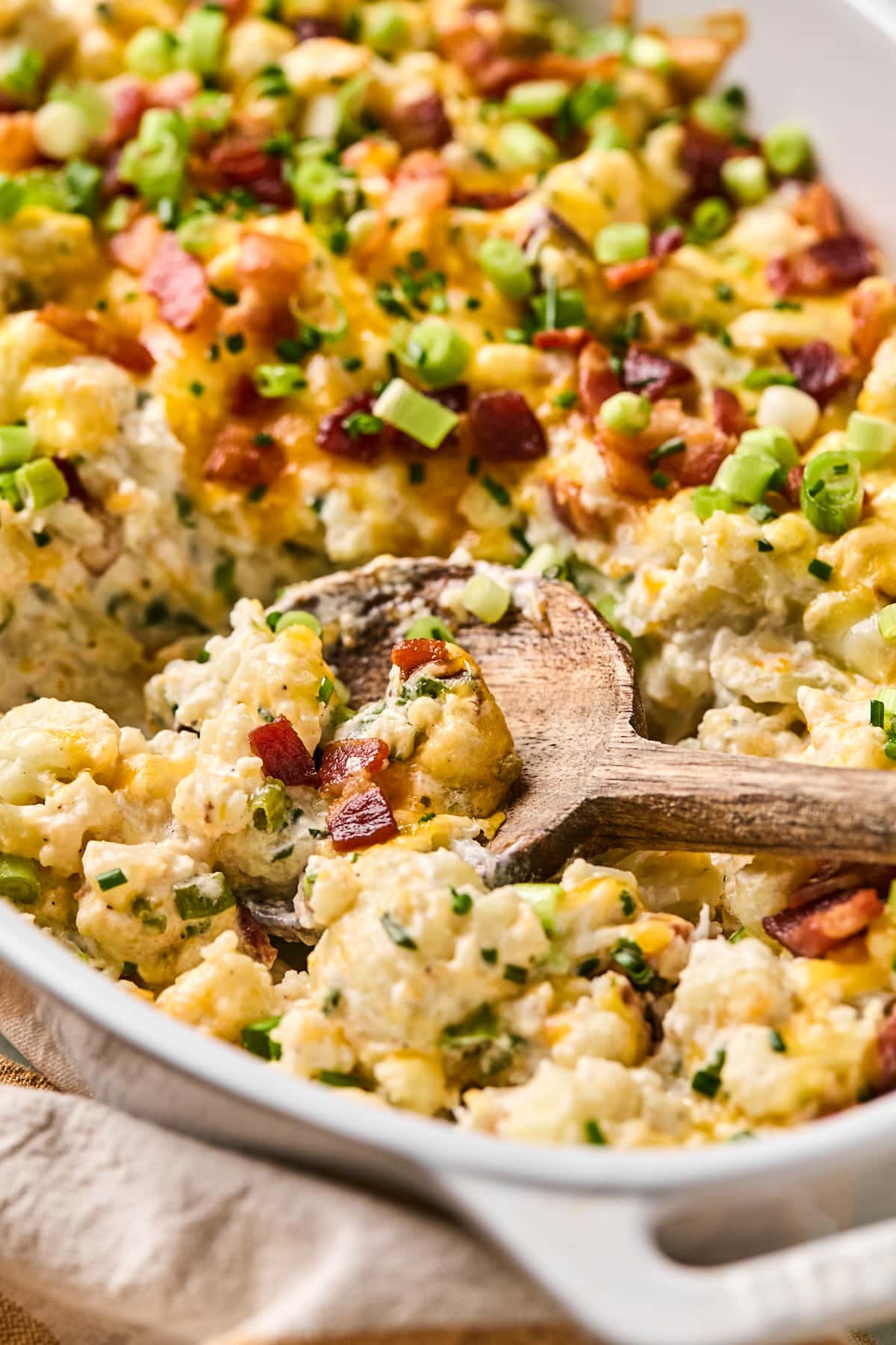 a few bites of loaded cauliflower casserole resting on a wooden spoon 