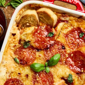 pizza dip with pepperoni and basil in a baking dish