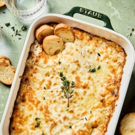 greek yogurt french onion dip in a baking dish topped with fresh thyme