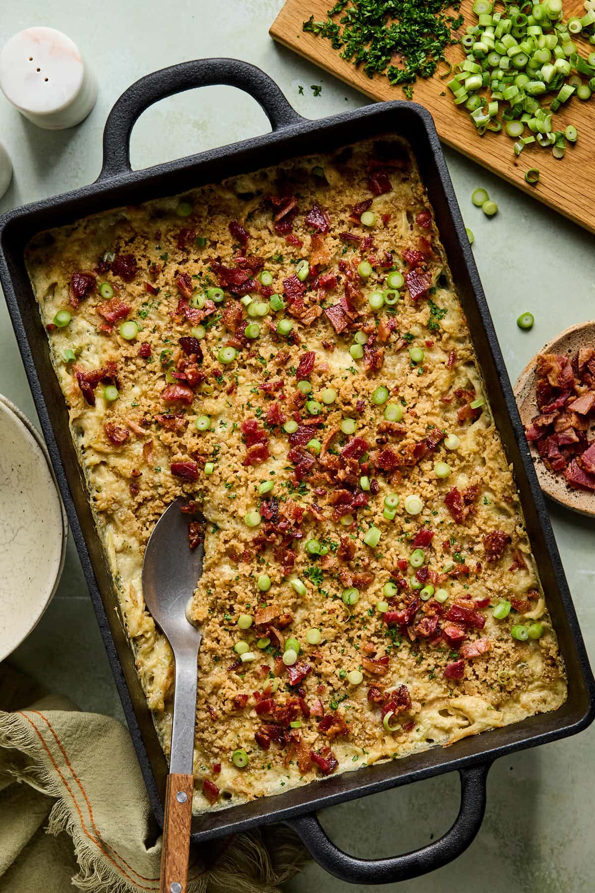 million dollar chicken casserole in a black baking dish with a metal spoon resting on the side. 