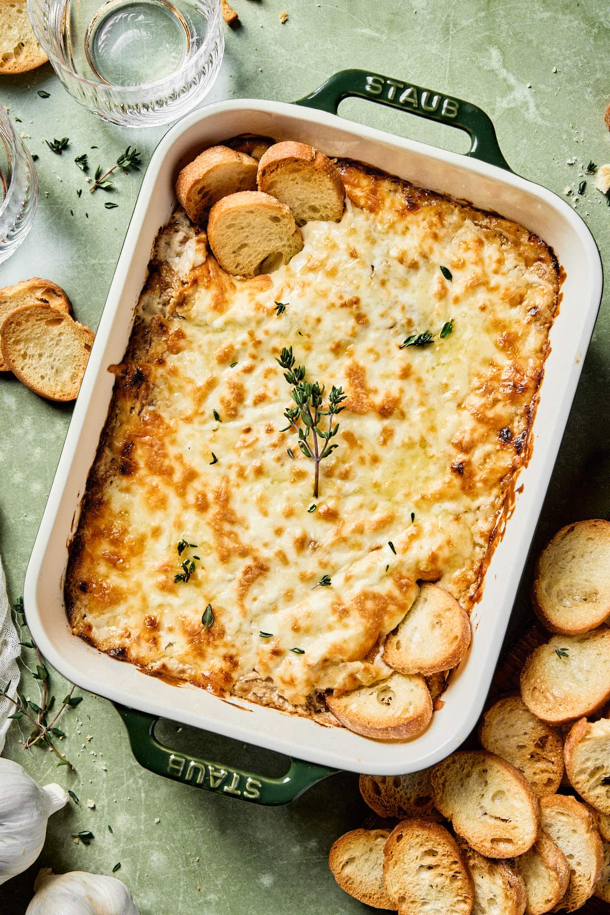 greek yogurt french onion dip in a baking dish topped with fresh thyme