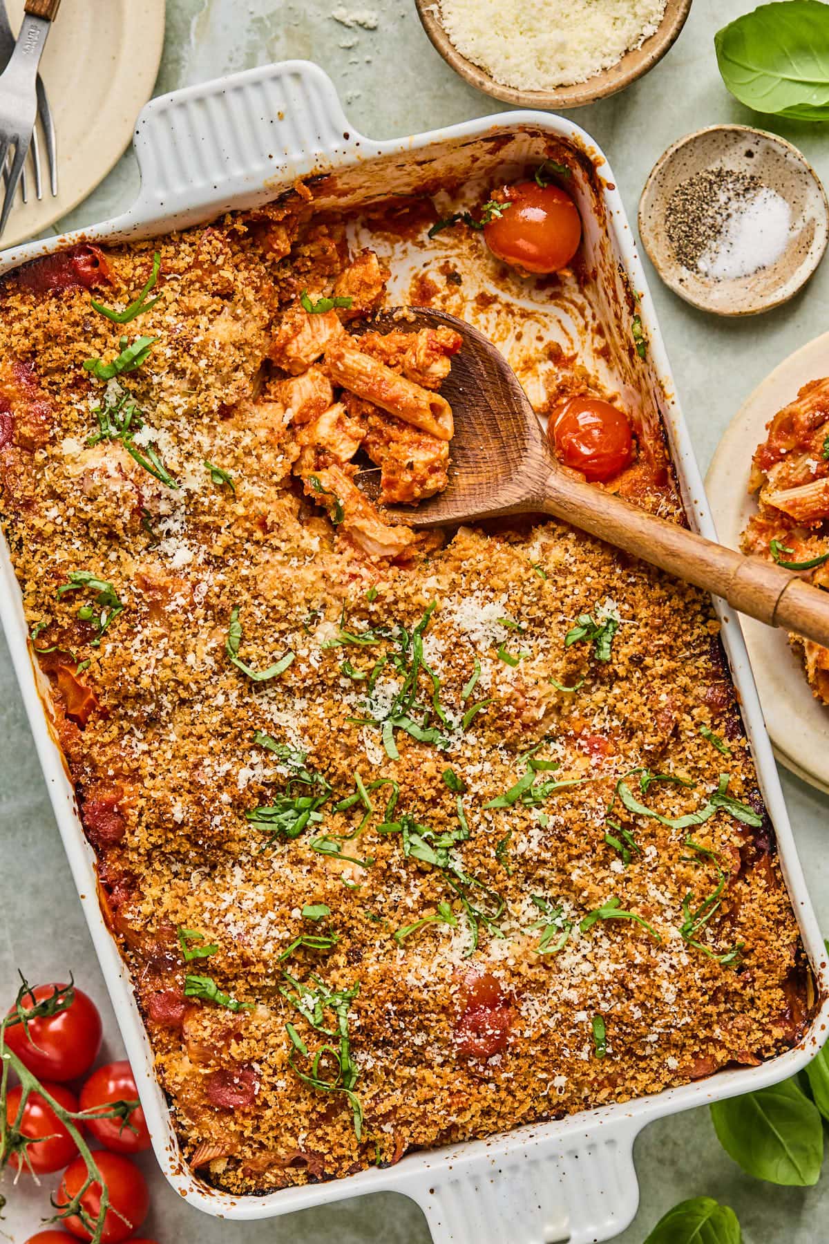 chicken parmesan casserole in a baking dish with a wooden spoon resting inside. 