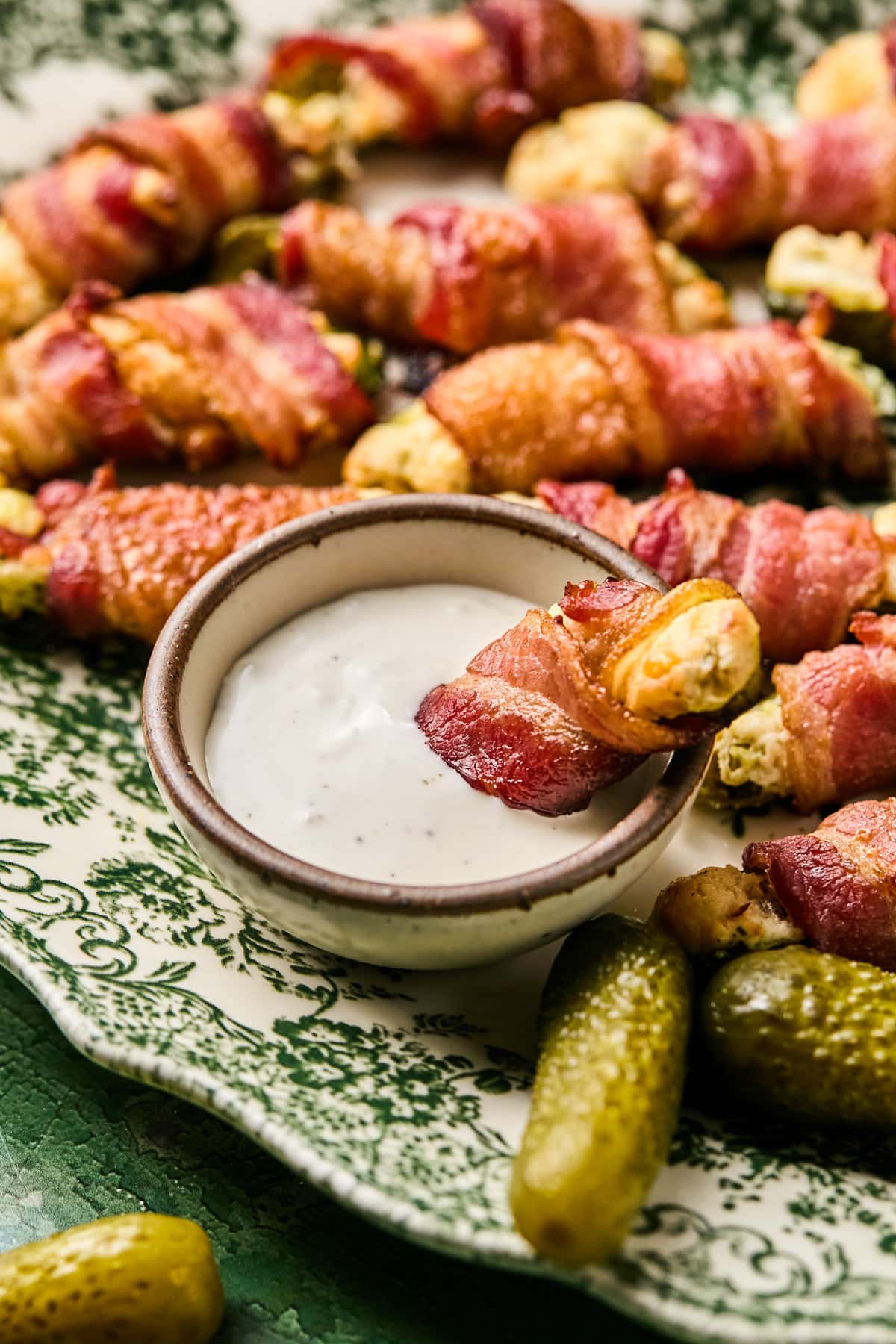 a pickle popper dipped in a bowl of ranch dressing 