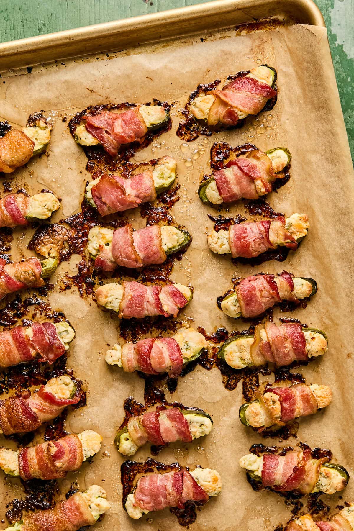 baked pickles wrapped in bacon on a piece of parchment paper