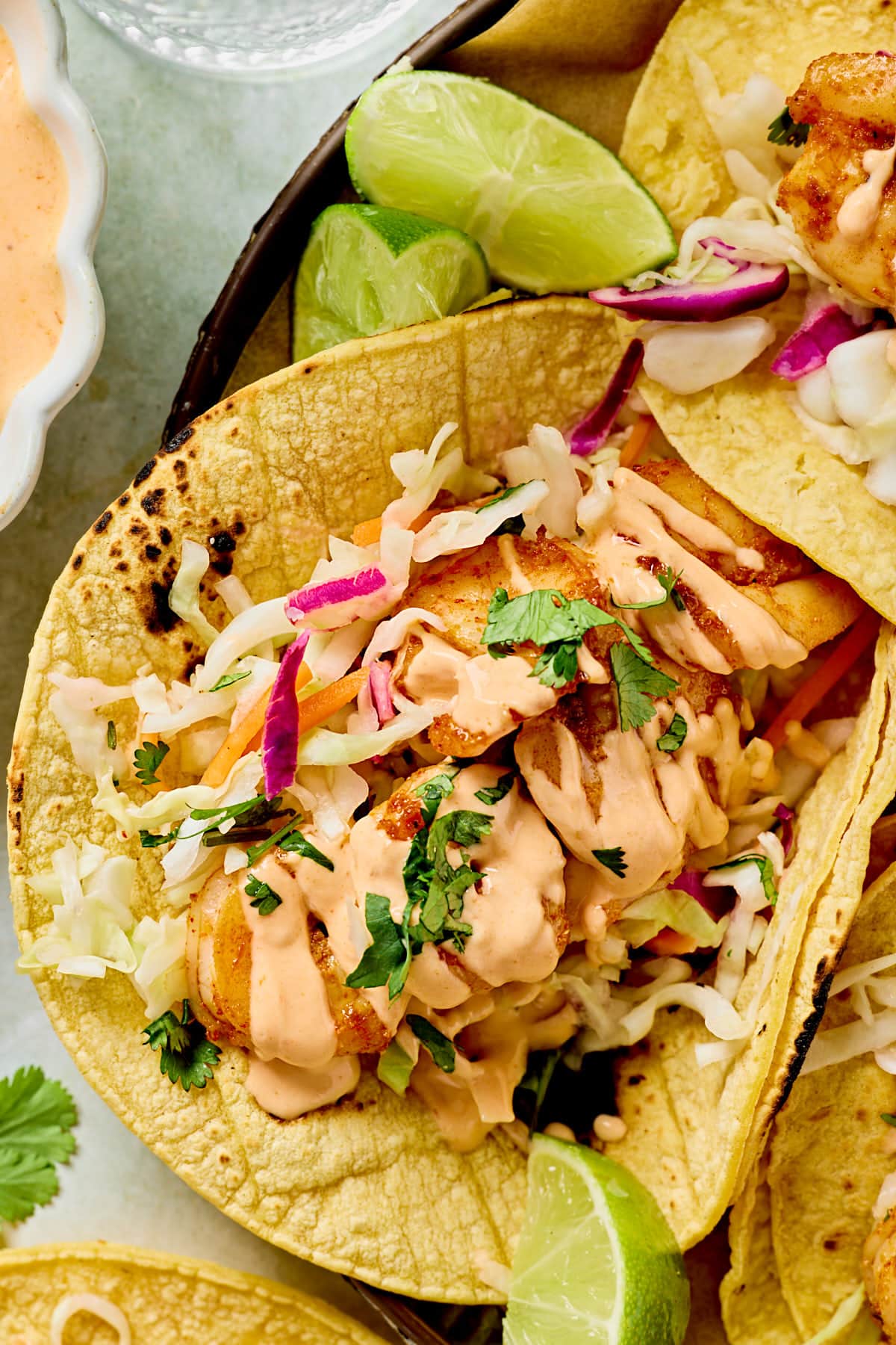 a close up photo of a bang bang shrimp taco topped with cilantro and bang bang sauce