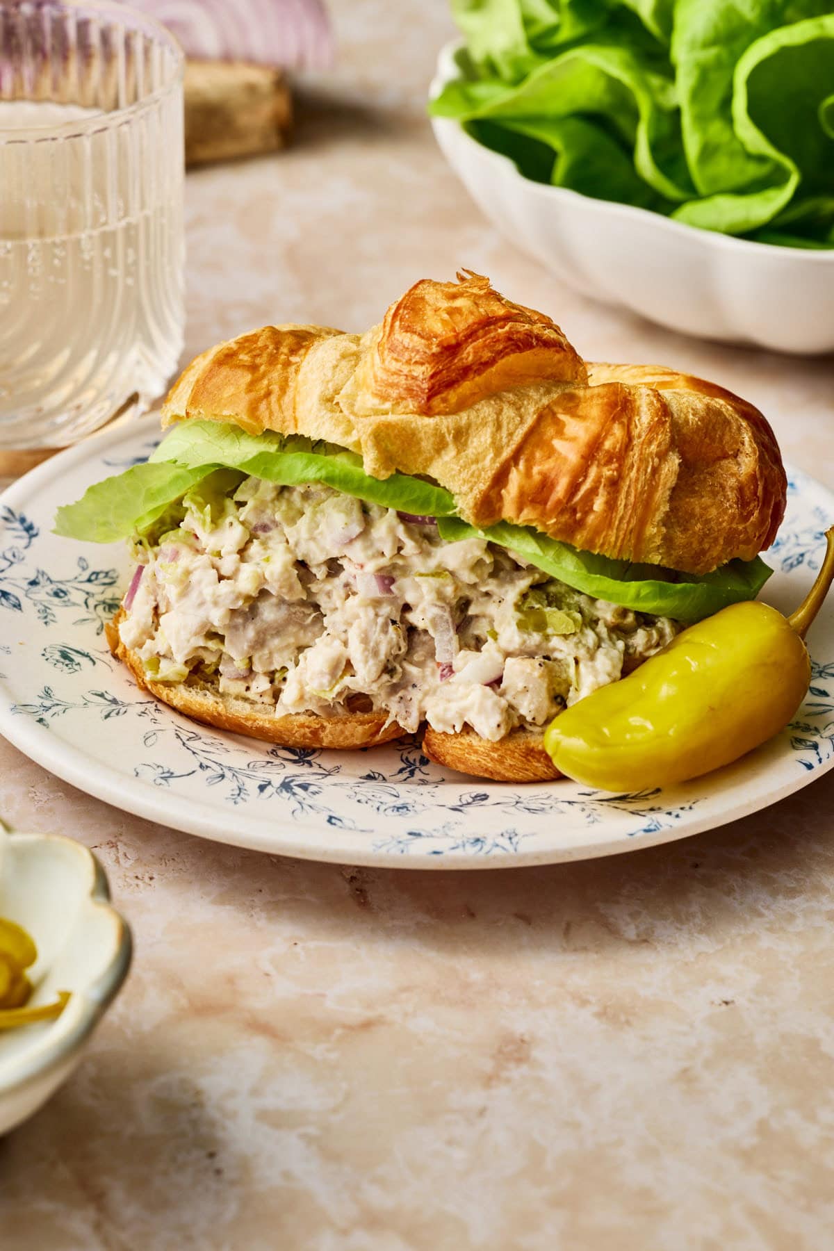 creamy pepperoncini chicken in a croissant with lettuce and a pepperoncini on the side