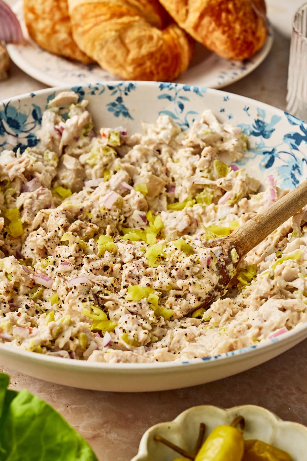 a wooden spoon scooping some creamy pepperoncini chicken from a bowl