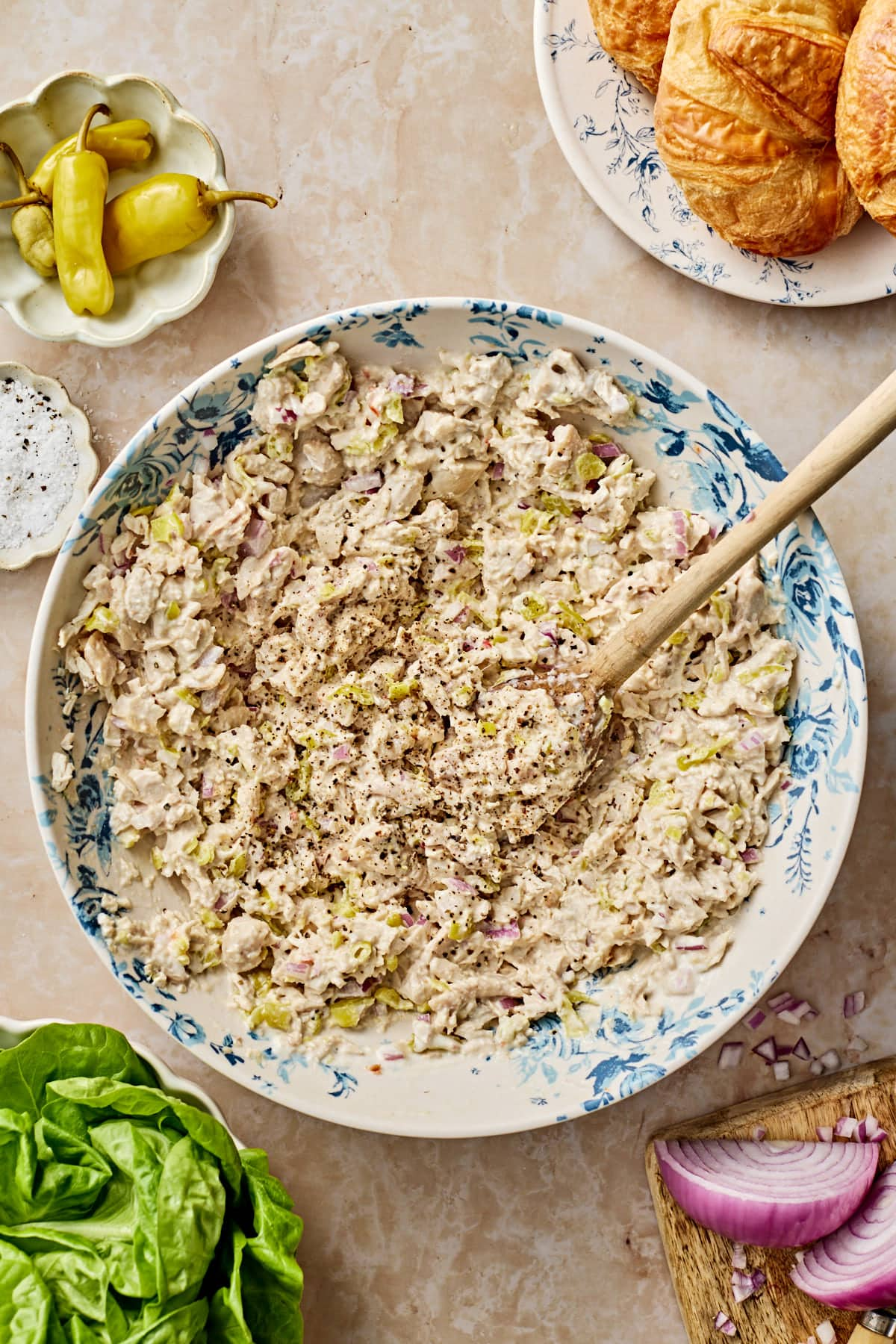 Creamy pepperoncini chicken in a bowl with a wooden spoon in the bowl with small plates in ingredients around it