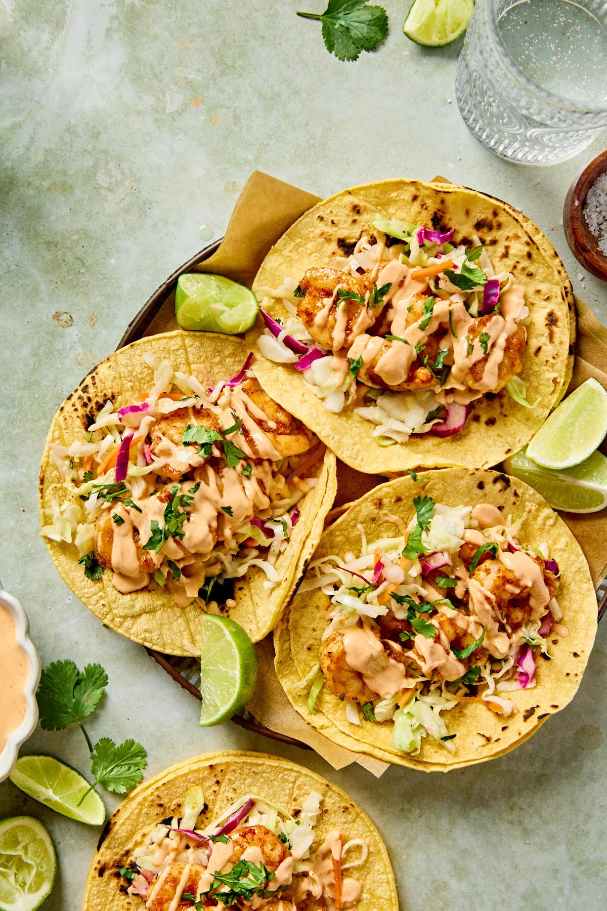 three bang bang shrimp tacos on a plate with lime slices as garnish