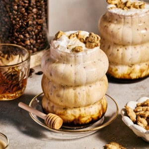 a teddy graham latte in a glass with honey drizzling over the top