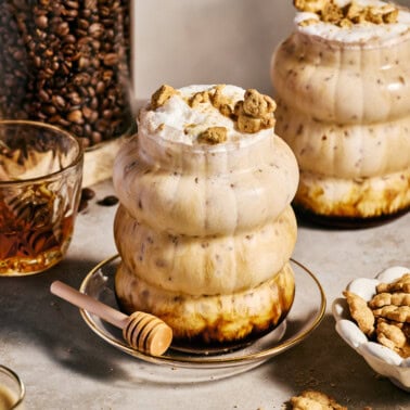 a teddy graham latte in a glass with honey drizzling over the top