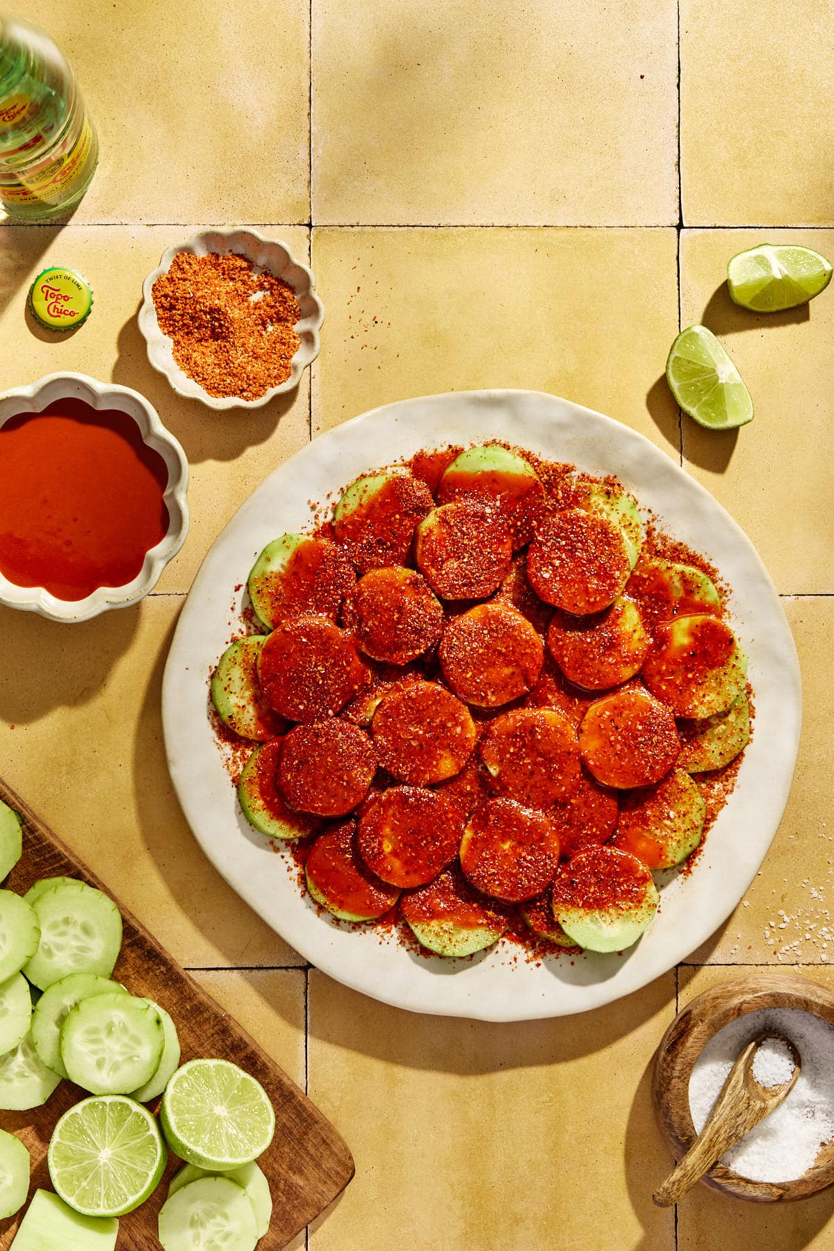 Mexican cucumbers on a white plate covered in hot sauce, lime juice, and tajin. 