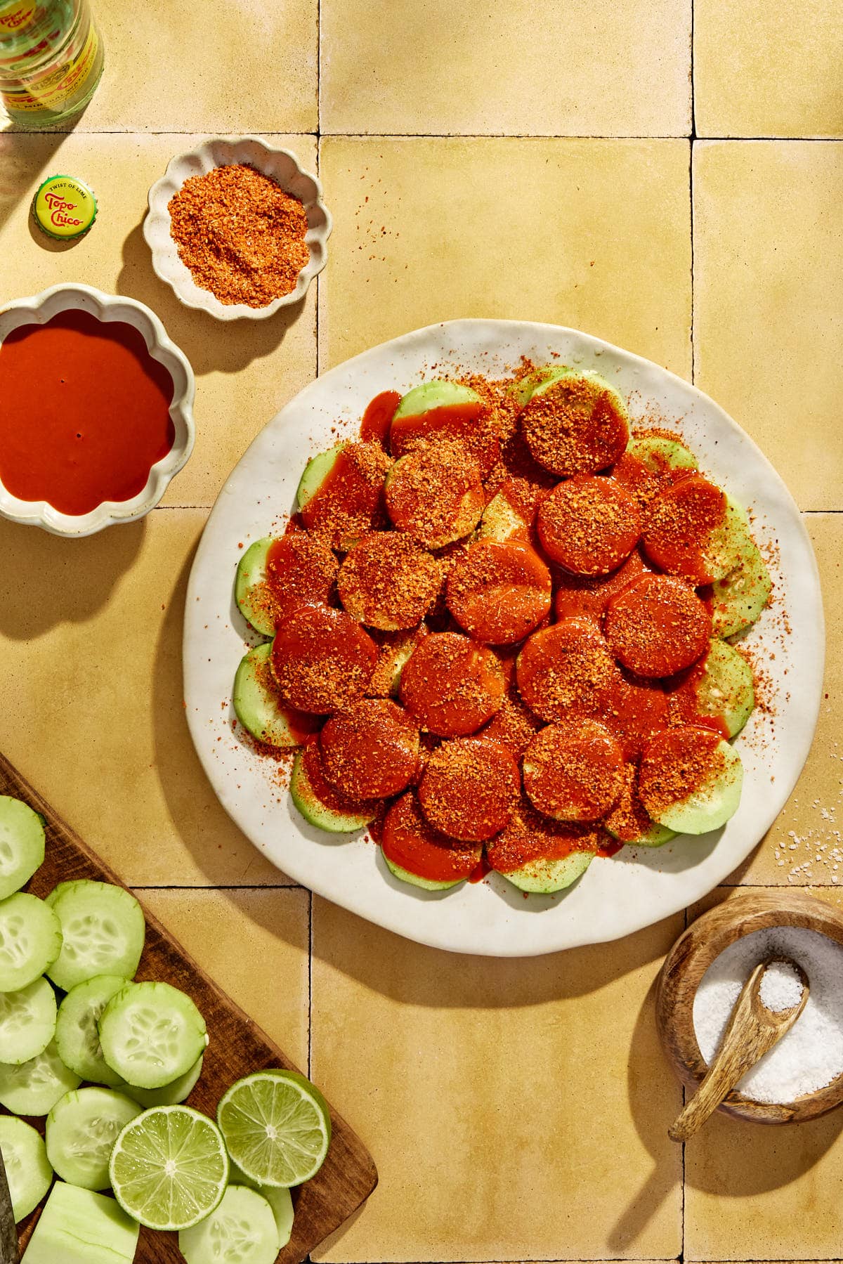 tajin seasoning sprinkled atop a plate of cucumbers with hot sauce. 