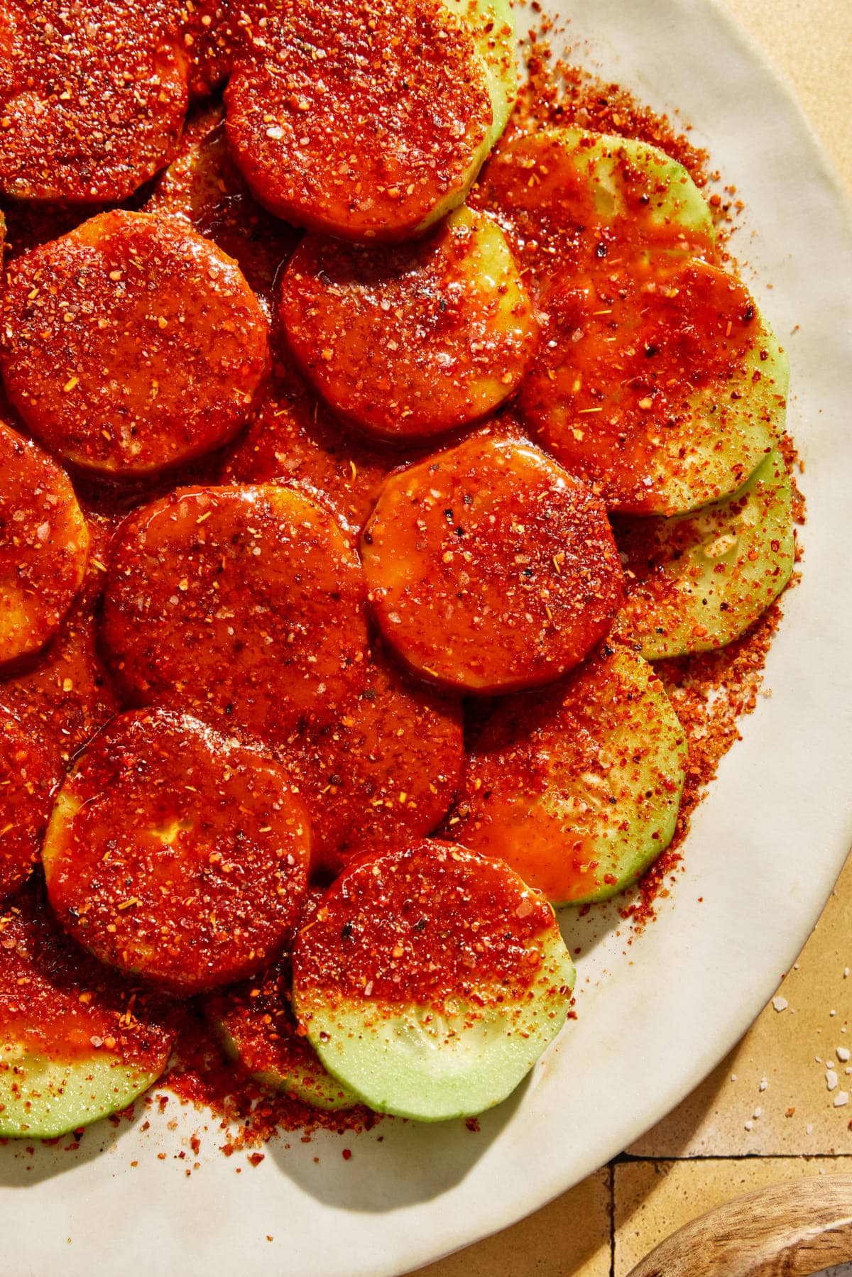 Mexican cucumbers on a plate covered in hot sauce, lime juice, and tajin seasoning. 